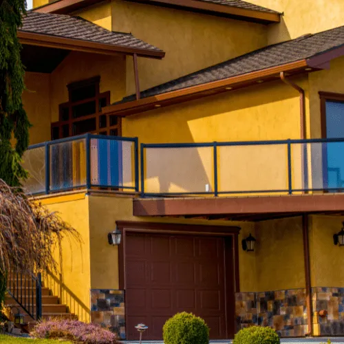 Two-story home with vivid golden stucco, a stone wainscot, and a balcony